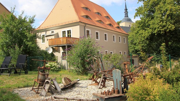 A traditional building with a sloped roof, a balcony, and a tower with a dome. - Apartment in historic surroundings (Müglitztal)