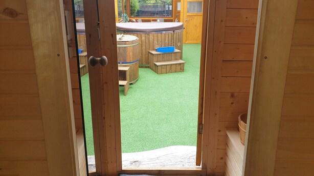 Una terraza de madera con un jacuzzi, una mesa de madera y una palangana azul.