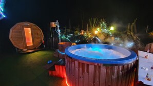 Un jacuzzi con revestimiento de madera y una terraza de madera en frente.