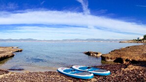 A coastal scene with two blue paddleboards on a rocky shore.