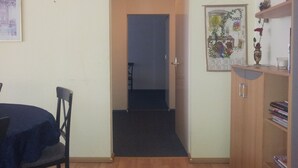Quarto com mesa de jantar, cadeiras, um armário de madeira e uma porta que dá para outro cômodo.