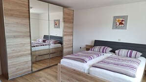 Un dormitorio con una cama de madera, un armario espejado y un cuadro en la pared.