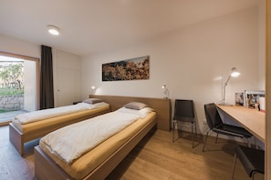 Une chambre avec deux lits, un bureau, une chaise et une bibliothèque.