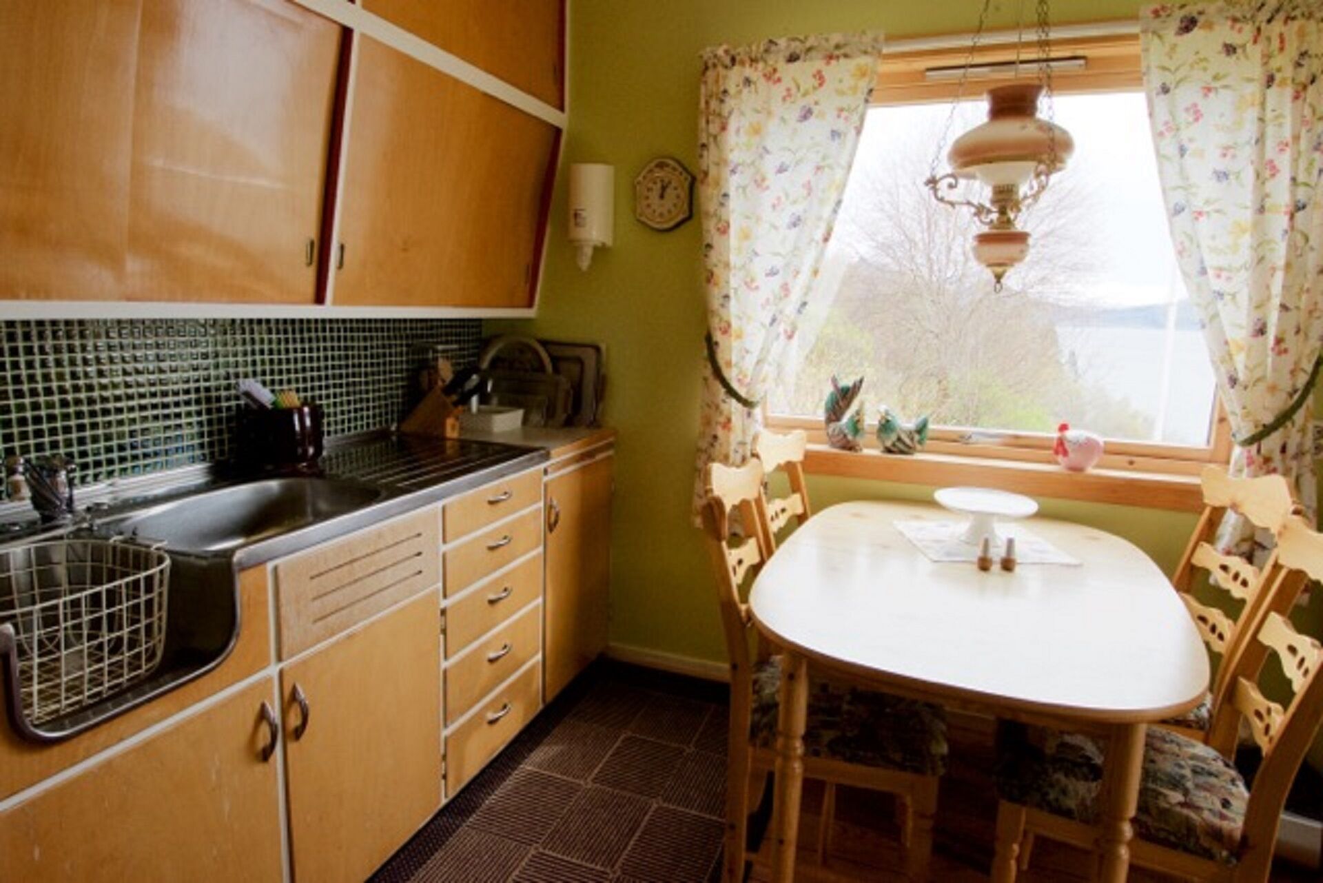 Una cocina con armarios de madera, un lavamanos y una zona de comedor con una mesa y sillas.