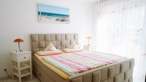 Ein Schlafzimmer mit einem Bett, zwei Nachttischen, einem Fenster mit Vorhängen und einem Bild an der Wand.