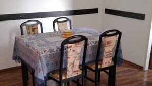 A dining table with a patterned tablecloth, four chairs, and a small decorative item on the table.