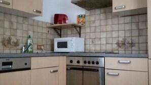 A kitchen with beige cabinets, a microwave, a toaster, and a stove.