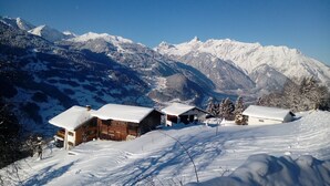 A snow-covered mountain landscape with wooden cabins and a clear sky.