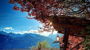 A wooden gazebo with a view of mountains and a lake.