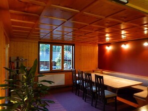 A wooden-paneled room with a dining table and chairs, a bench, and a window with blinds.
