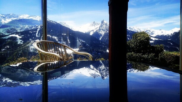 A chair reflected in a glass window with a mountain view.