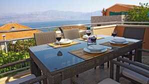 A dining table set with plates, glasses, and cutlery on a balcony overlooking a scenic view.