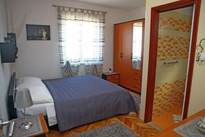 Une chambre à coucher avec un lit, une table de chevet, une lampe et une vue sur le paysage urbain par la fenêtre.