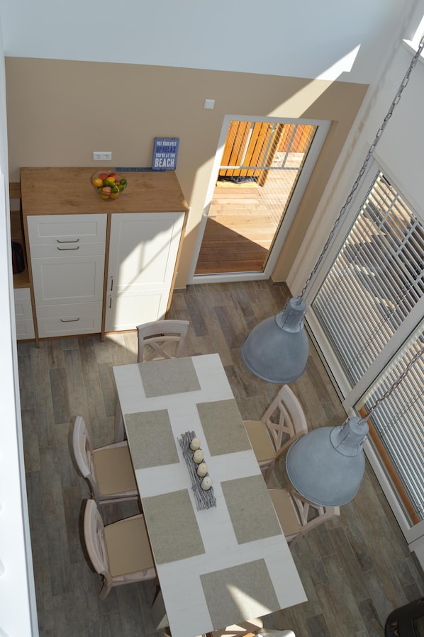 A compact kitchen with a wooden countertop, a dining table with chairs, and a hanging light fixture. - Private beach! NEW villa "Cloudless" with fireplace and sauna right on the beach (Löbnitz)