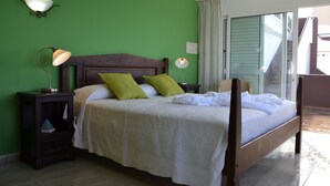A bedroom with a bed, green walls, two bedside lamps, a nightstand, and a view of the outside. - Apartment directly on the sea with a fantastic view in Punta del Hidalgo (La Laguna / Punta del Hidalgo)