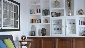 A living room with a grey sofa, a small table with fruits, and a bookshelf filled with books and decorative items. - Apartment directly on the sea with a fantastic view in Punta del Hidalgo (La Laguna / Punta del Hidalgo)
