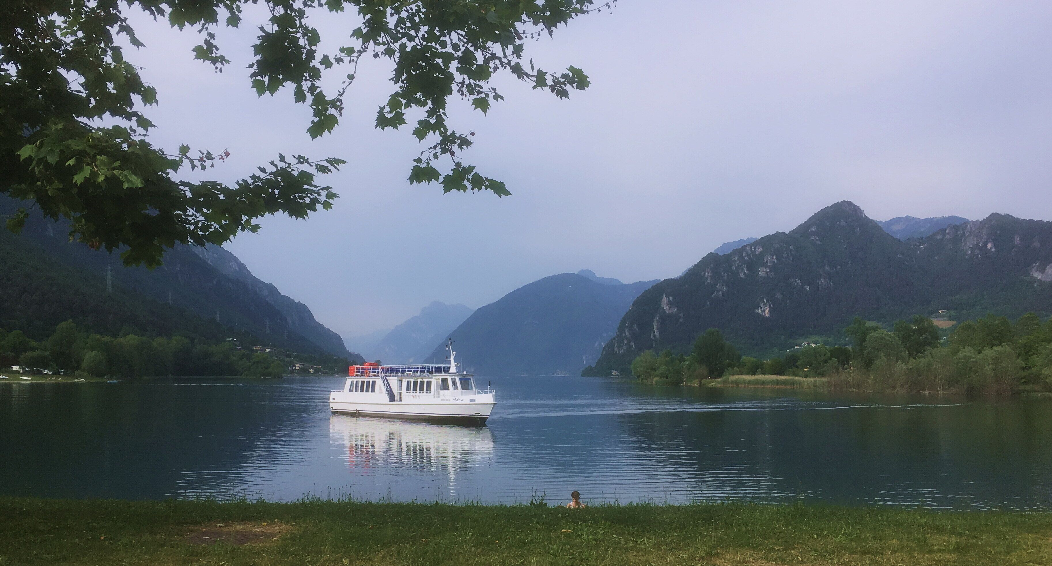 A boat on a calm lake surrounded by mountains.