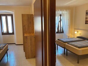 Ein Schlafzimmer mit zwei Betten, einem Holzschrank und einem Fenster mit Vorhängen.