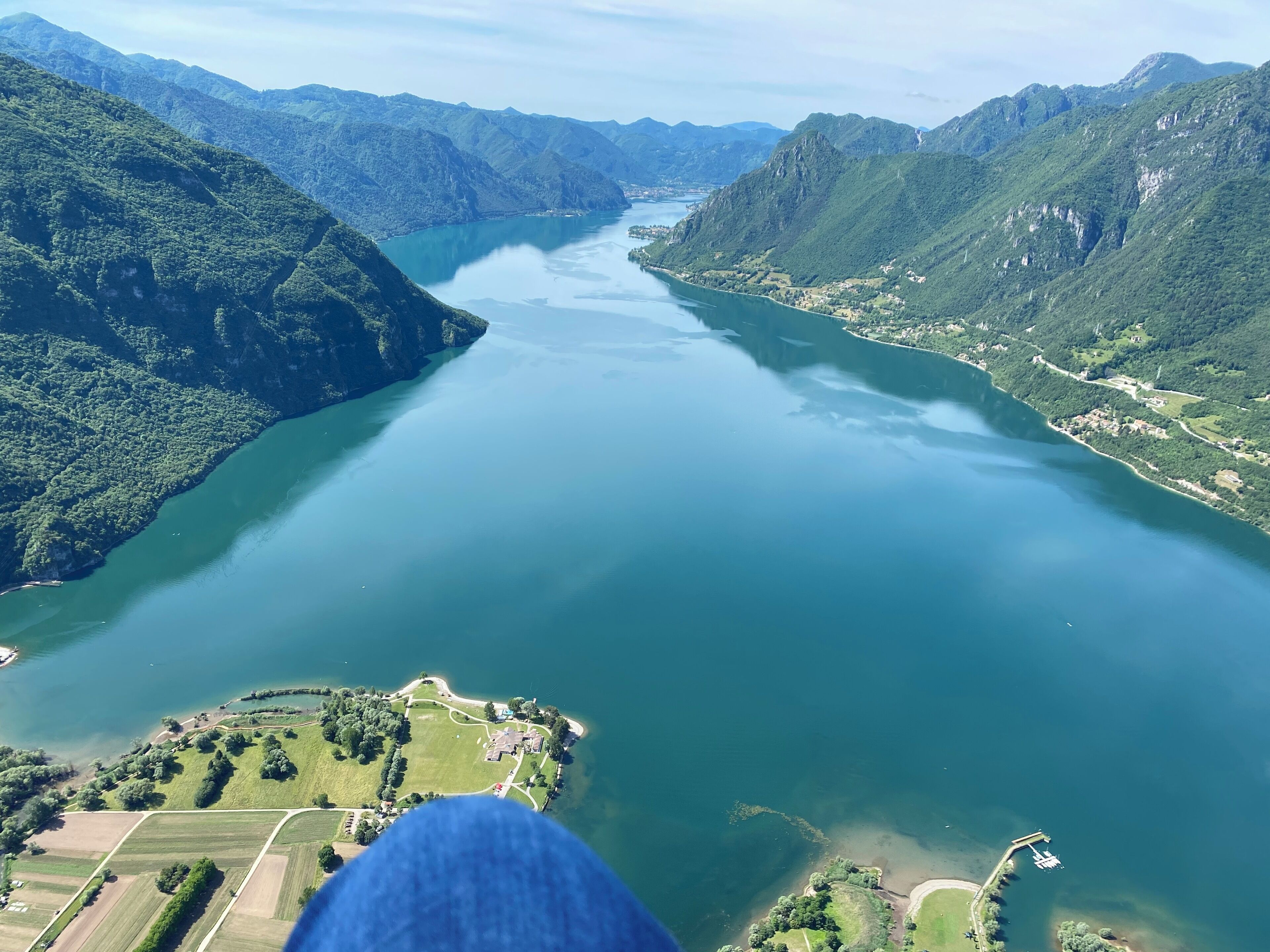 Une vue aérienne d’un lac entouré de montagnes, avec une petite île abritant un bâtiment et des sentiers.