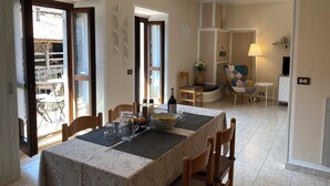 En spiseplads med et bord dækket til to personer, en stol, en lampe og udsigt til den udendørs balkon.
