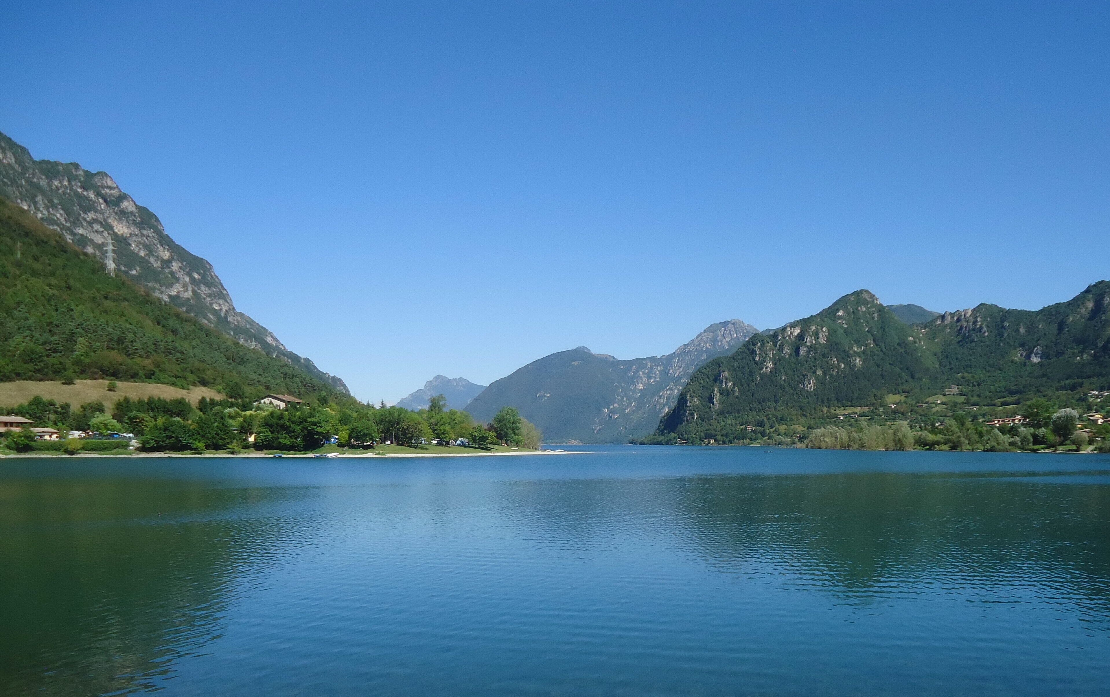 Un lago sereno rodeado de montañas y un cielo despejado.