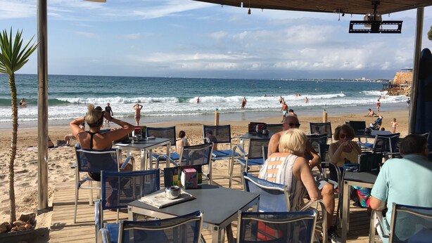 A beachside cafe with outdoor seating overlooking the ocean.