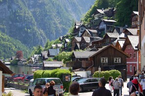 A mountainous village with traditional wooden houses, a lake, and a pedestrian walkway.