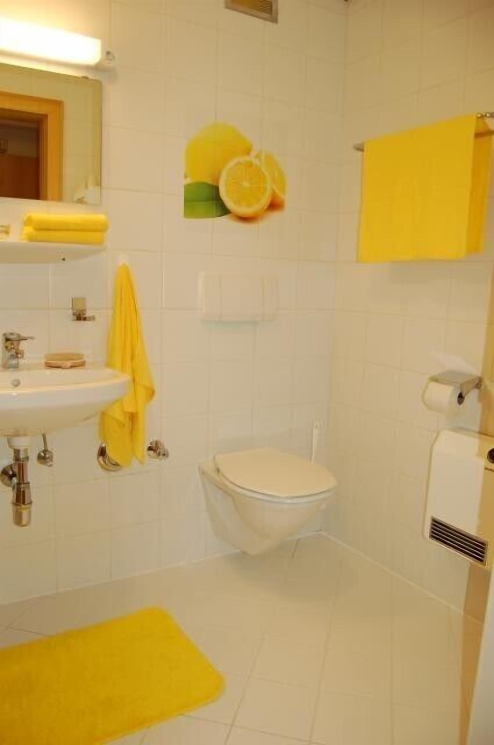 A bathroom with a sink, toilet, and yellow towels.