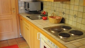 A kitchen with wooden cabinets, a stove, a microwave, and a red rug. - Apartment, 300m to the ski slope, everything on site, gr. Leisure offer winter + summer (Rußbach)