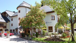A traditional European hotel with a central courtyard, outdoor seating, and a mountain backdrop. - Apartment, 300m to the ski slope, everything on site, gr. Leisure offer winter + summer (Rußbach)