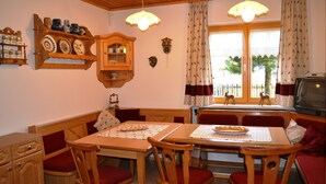 Un comedor acogedor con muebles de madera, una mesa dispuesta con platos y un televisor en una esquina.