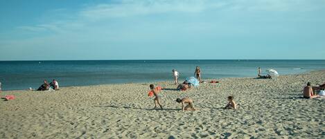 Een zandstrand met mensen die zonnebaden en spelen.