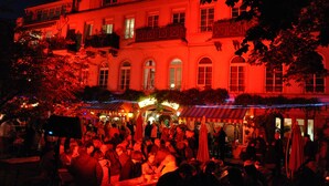 A historic building with a crowd gathered outside, featuring an arched entrance and outdoor seating areas. - Apartment Marion Altenkirch (Rüdesheim am Rhein)