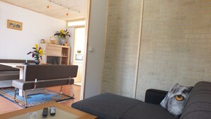 A living room with a grey sofa, a wooden coffee table, and a dining area with a bench.