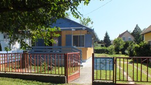 A fenced property with a wooden structure, a paved pathway, and a signboard.