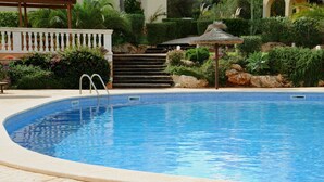 Une piscine à l’eau d’un bleu limpide, entourée d’une zone pavée et d’une végétation luxuriante.
