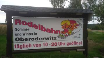 A sign advertising a sledding area open daily from 10-20 Uhr.