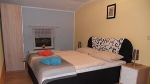 Un dormitorio con cama, mesita de noche, ventana con cortina e imagen colgada en la pared.