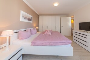 A bedroom with a bed, bedside tables, a TV, and a wardrobe.