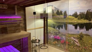 A spa room with a wooden bench, a small table with a candle, and a wall mural of a lake and mountains.
