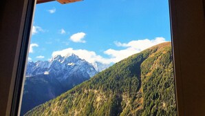 Un paisaje montañoso visto a través de una ventana, con una viga de madera en el techo.