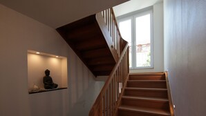 A wooden staircase with a handrail, leading to a landing with a small shelf holding a statue. - quiet accommodation in a central location 2km to Heidelberg (Leimen)
