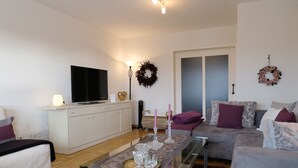 A living room with a sofa, a coffee table, a TV, and a fireplace. - quiet accommodation in a central location 2km to Heidelberg (Leimen)