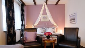 A bedroom with a bed, two chairs, a small table with a vase of flowers, and a window with curtains. - quiet accommodation in a central location 2km to Heidelberg (Leimen)