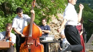 Un grupo de músicos actuando al aire libre, con un violonchelo y otros instrumentos.