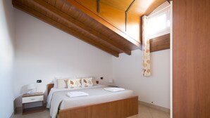A bedroom with a wooden bed frame, a nightstand with a lamp, and a window with a curtain.