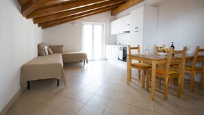 A compact living space with a dining area, kitchenette, and a bench.