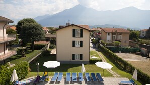 A building with a garden and lounge chairs in front.
