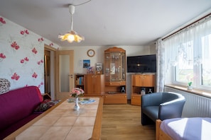 A living room with a sofa, a coffee table with a vase, a television, and a cabinet.