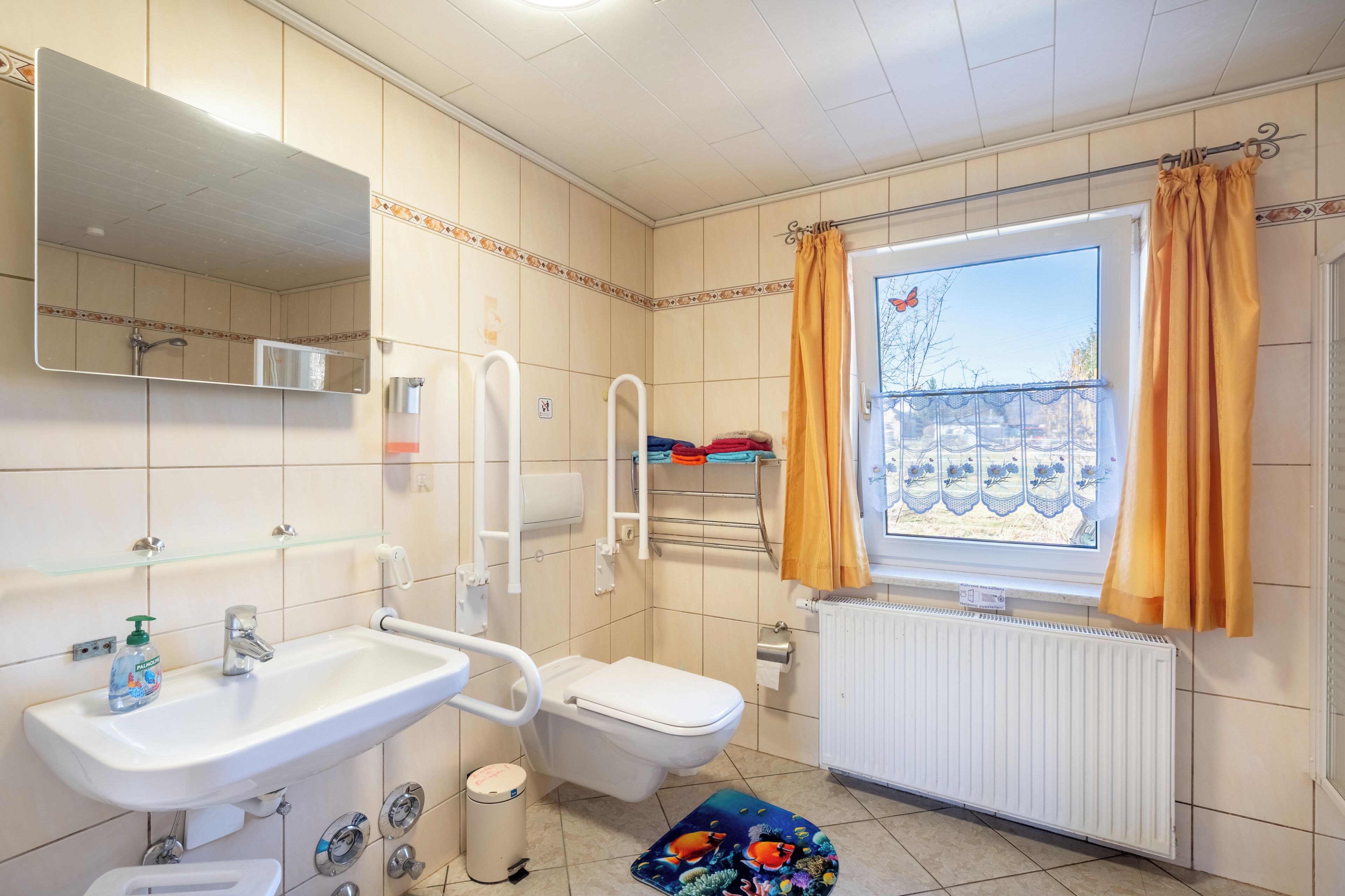 Een badkamer met een wastafel, toilet en raam voorzien van gordijnen.